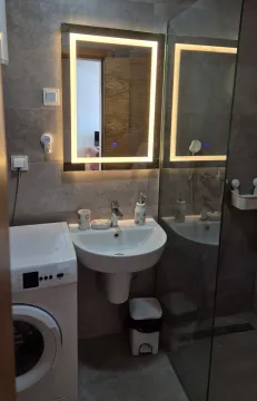 Bathroom with a washbasin, illuminated mirror, washing machine, and glass shower cabin. - image 14