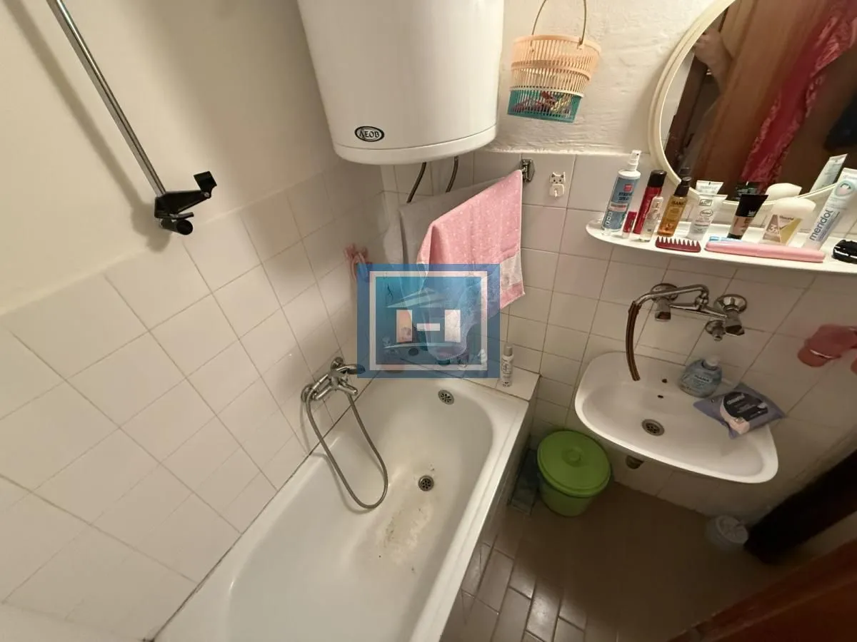Smaller bathroom with a bathtub, washbasin, and wall-mounted water heater.
