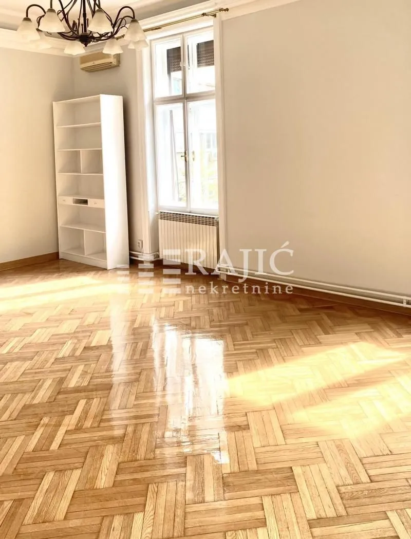 Empty room with parquet flooring and a white shelving unit.