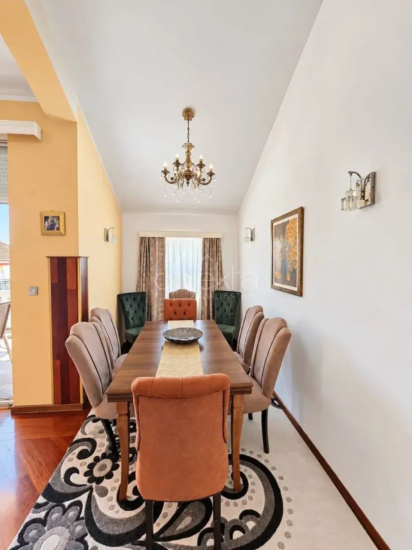 Dining area with a large wooden table and colorful chairs.