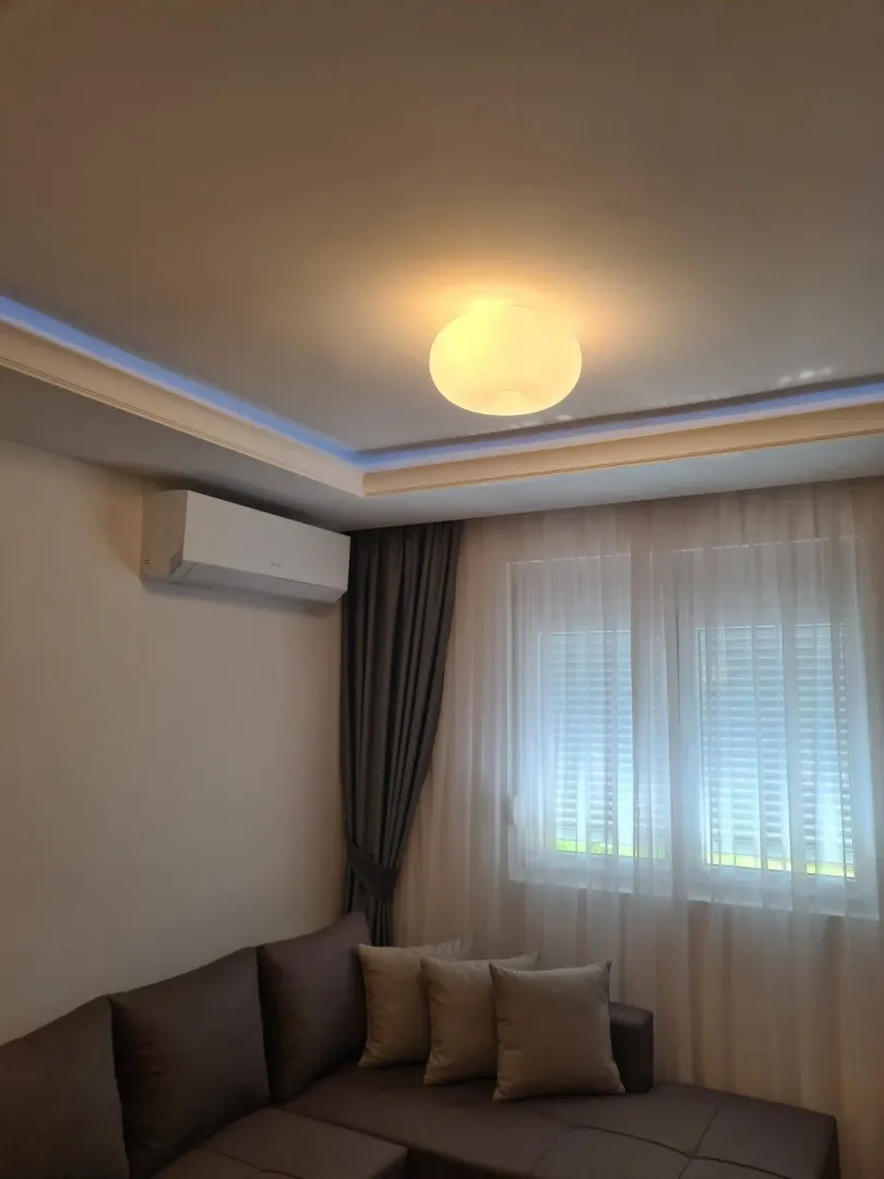 Cozy living room with a sofa, air conditioner, and window.