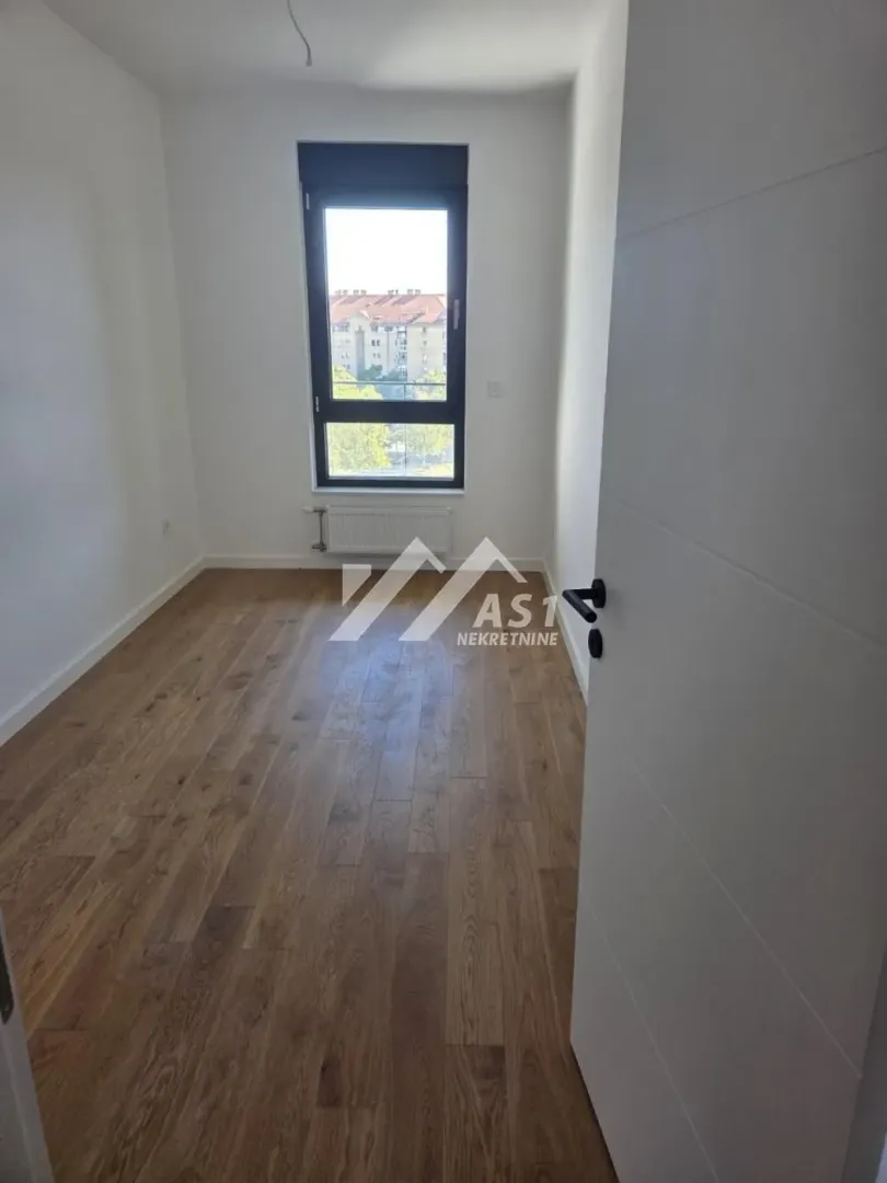 Empty room with parquet flooring and a window.