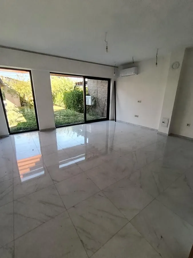 Empty living room with large glass sliding doors and a view of the courtyard.