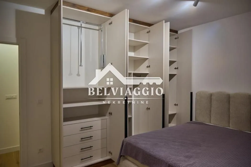Bedroom with a double bed and a large built-in wardrobe with open doors.