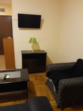 Living room with an armchair, wall-mounted TV, and coffee table. - image 4