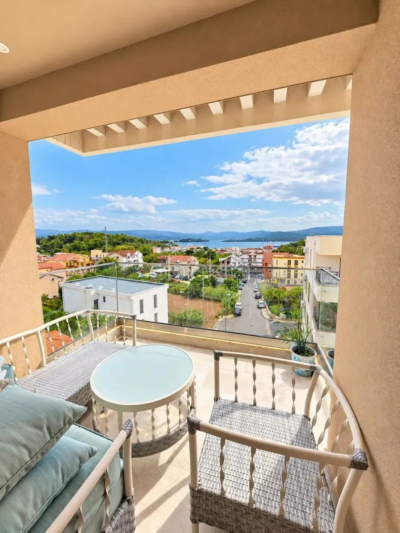 Natkriveni balkon sa garniturom za sjedenje i pogledom na naselje i more.