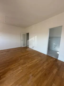 Prazna soba sa parketom i otvorenim prolazom ka prostoriji sa pločicama. - image 4