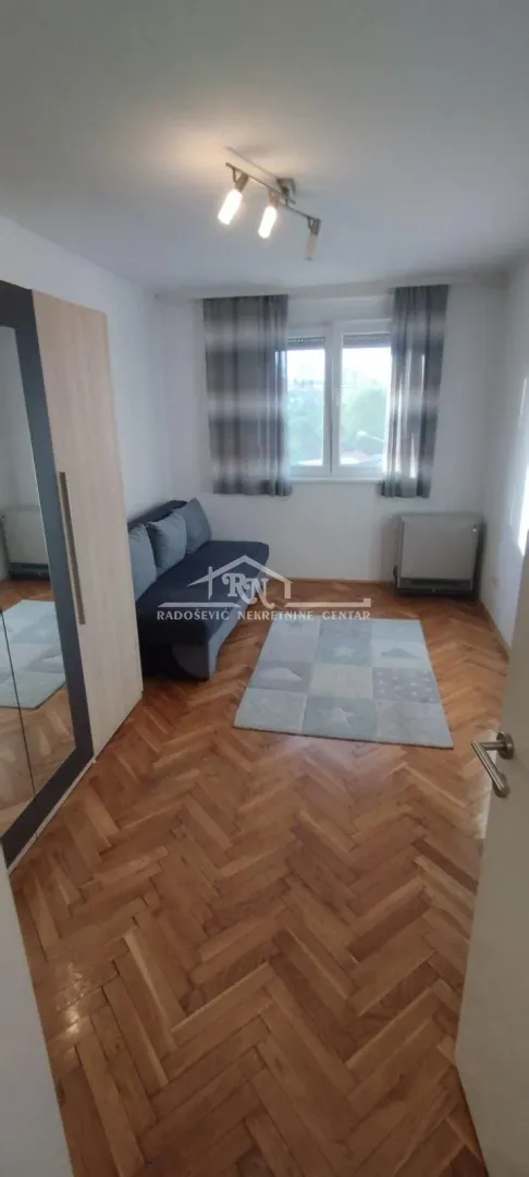 Smaller bedroom with a pull-out sofa, wardrobe and parquet flooring.