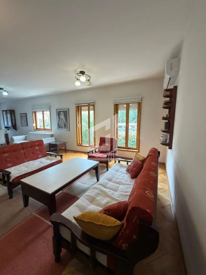 Spacious living room with seating furniture and wooden flooring.