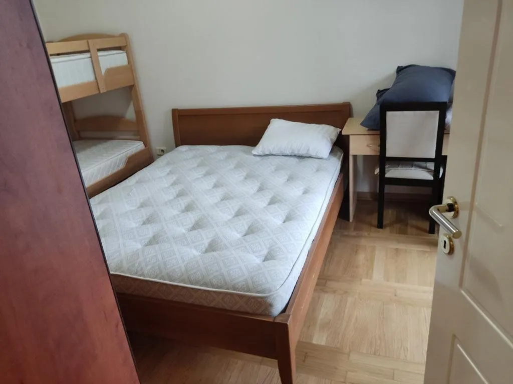 Spavaća soba sa bračnim krevetom, krevetom na sprat i radnim stolom.