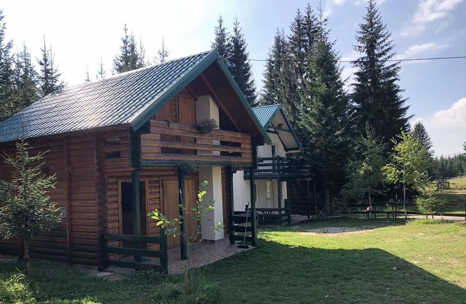 Drvene planinske kuće okružene borovom šumom i prostranim dvorištem.