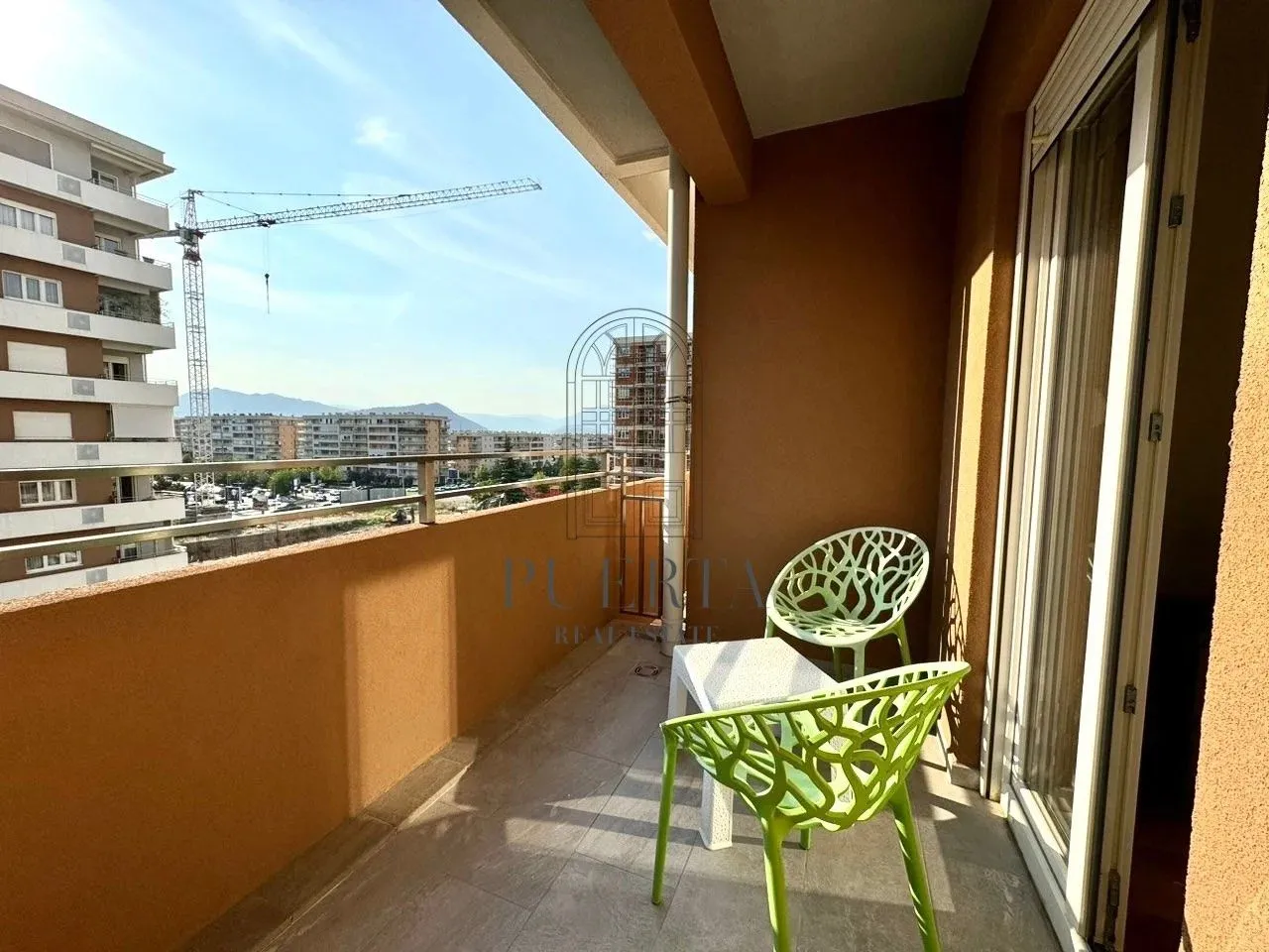 Furnished balcony with seating set and city view.