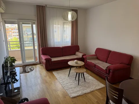 Svijetla dnevna soba sa crvenim kaučevima i izlazom na balkon. - image 4