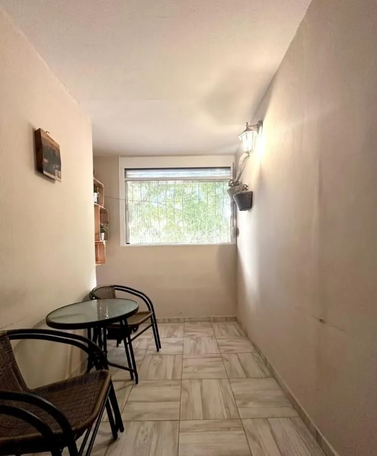 Zastakljeni balkon sa malim stolom i stolicama.