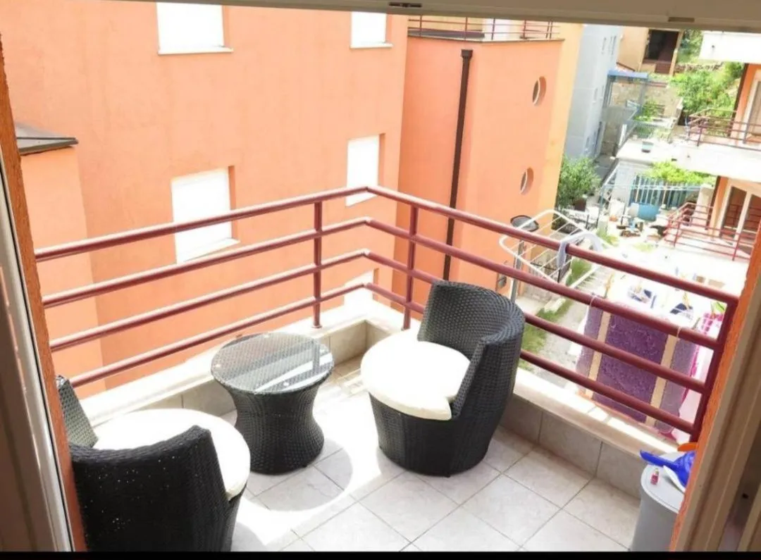 Small furnished balcony with seating set and view of surrounding buildings.