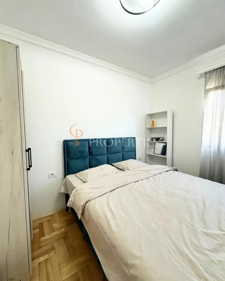Namještena spavaća soba sa bračnim krevetom i ormarom.