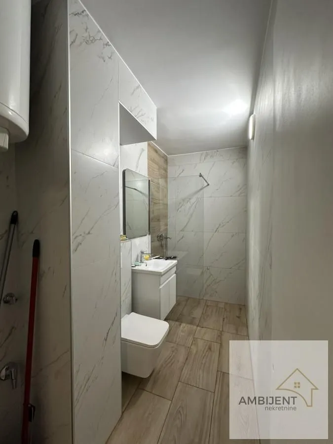 Savremeno opremljeno kupatilo sa tuš kabinom, umivaonikom i WC šoljom.