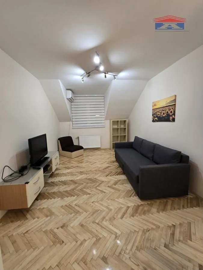 Dnevna soba sa garniturom, televizorom i drvenim podom.