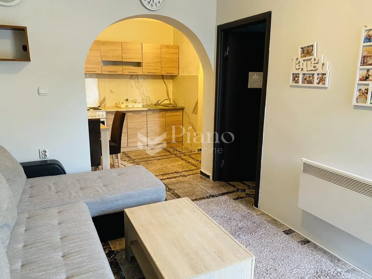 Living room with a sofa and a view of the kitchen through an archway.