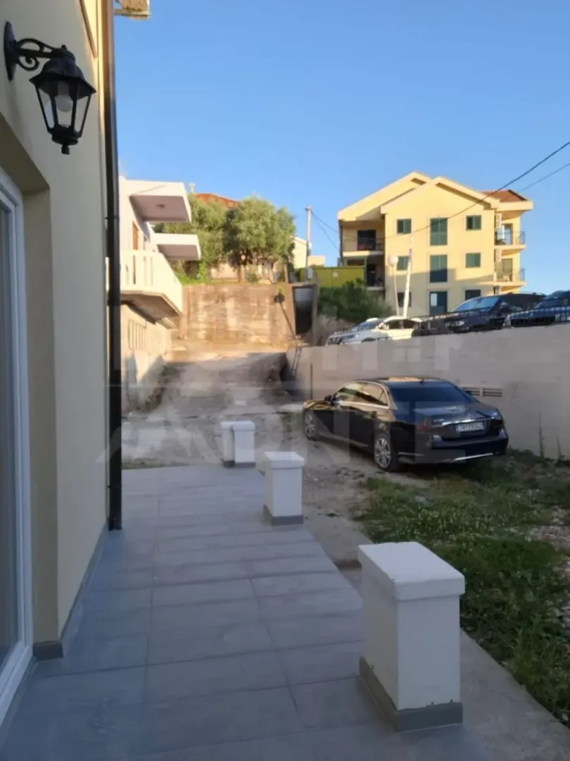 Pogled na spoljašnji dio objekta sa prilazom i parkiranim automobilom.