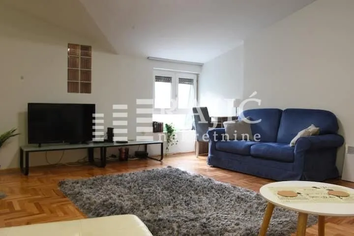 Living room with a blue sofa, TV, and parquet flooring.