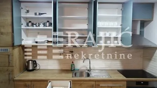 Modern kitchen with open upper cabinets and a built-in sink.