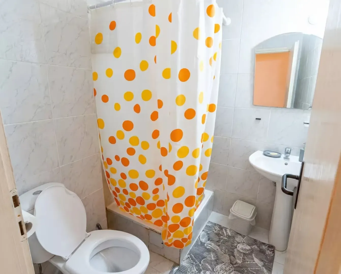 Bathroom equipped with a shower with a curtain, toilet, and washbasin.