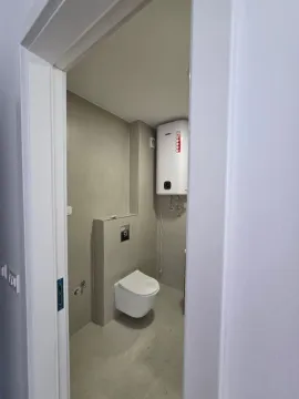 Pogled na moderno opremljeno kupatilo sa WC šoljom i bojlerom kroz otvorena vrata. - image 2