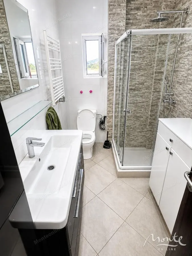 Modernly equipped bathroom with a shower cabin, washbasin, and toilet.