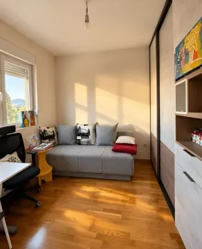 Small living room with a grey sofa, a desk, and a large wardrobe. - image 7
