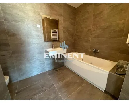 Bathroom equipped with a bathtub, washbasin, and stone-effect tiles. - image 16