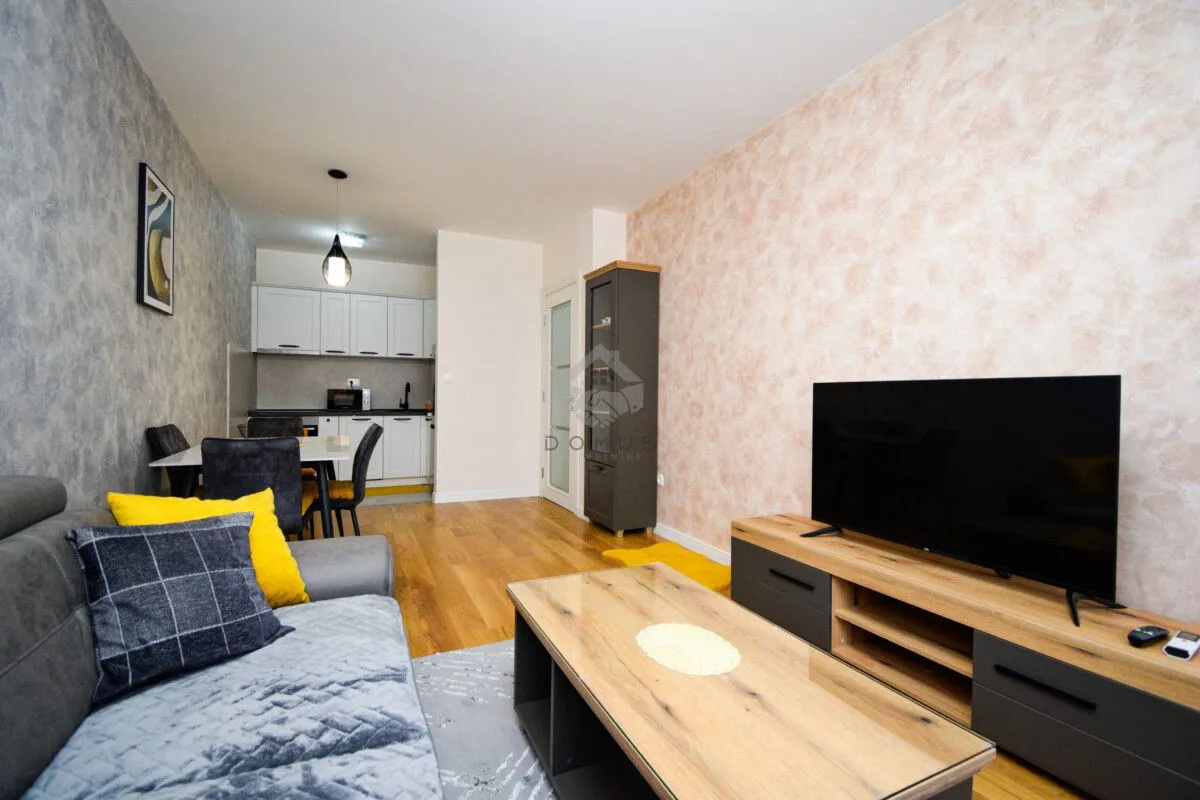 Living room with a sofa, TV, and an adjoining dining area.