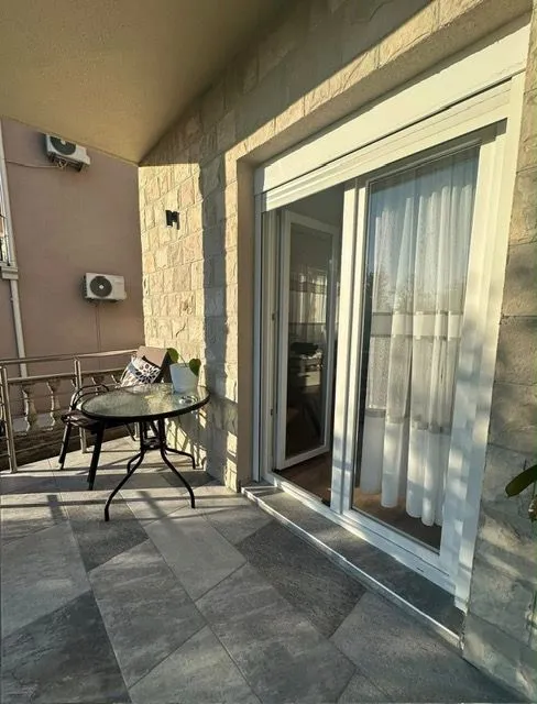 Natkrivena terasa sa stolom, stolicama i izlazom u enterijer.