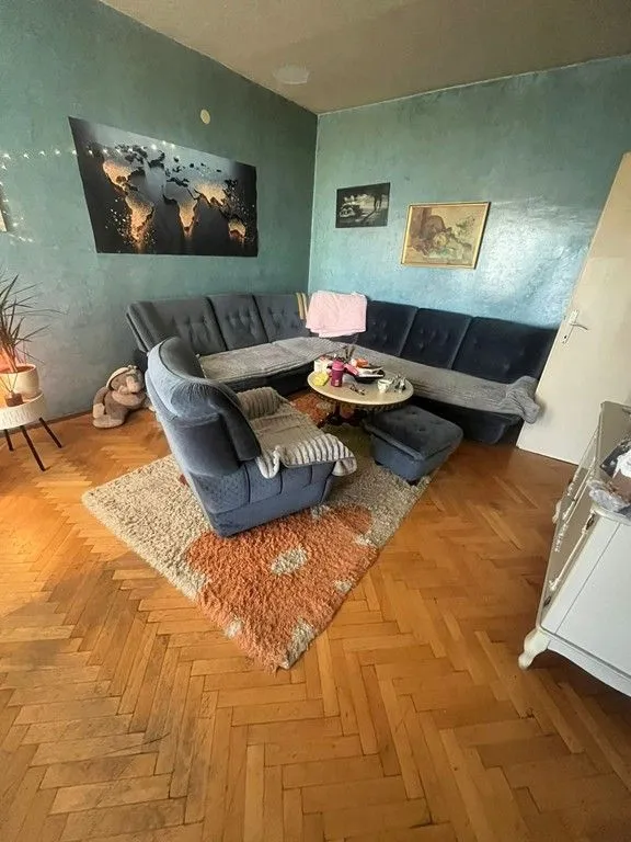 Dnevna soba sa garniturom za sjedenje, foteljom i parketom na podu.