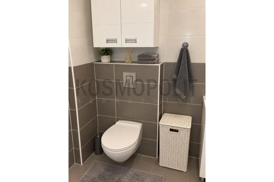View of a modernly equipped bathroom with a toilet, cabinet, and laundry basket.