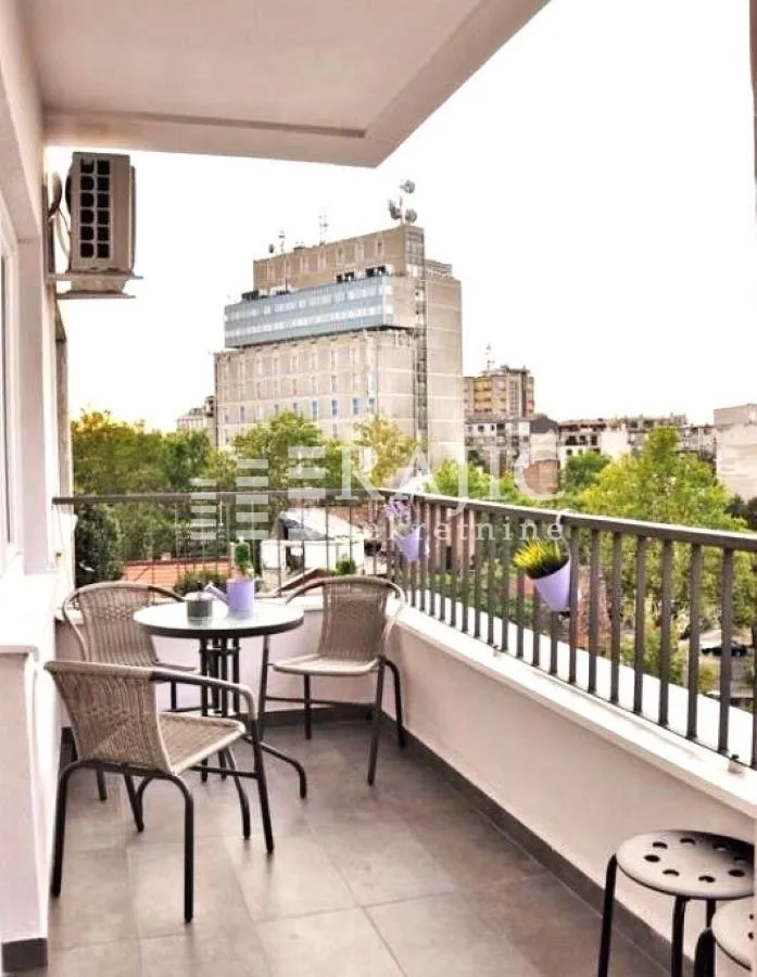 Furnished balcony with seating set and city view.