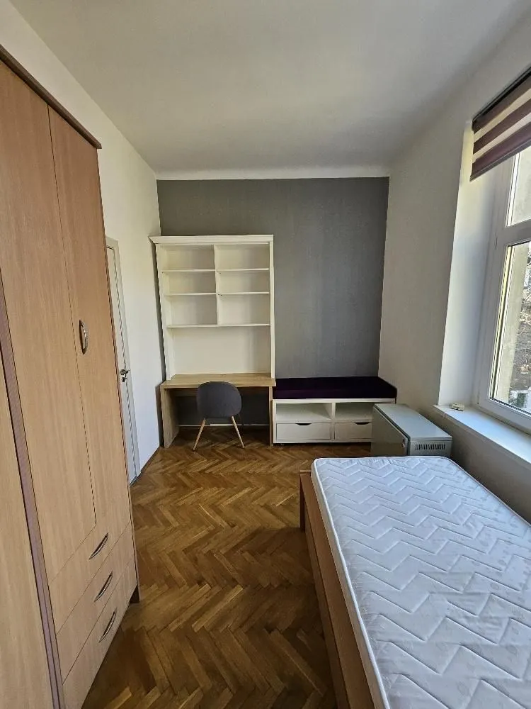 Manja spavaća soba sa krevetom, garderoberom, radnim stolom i policama.
