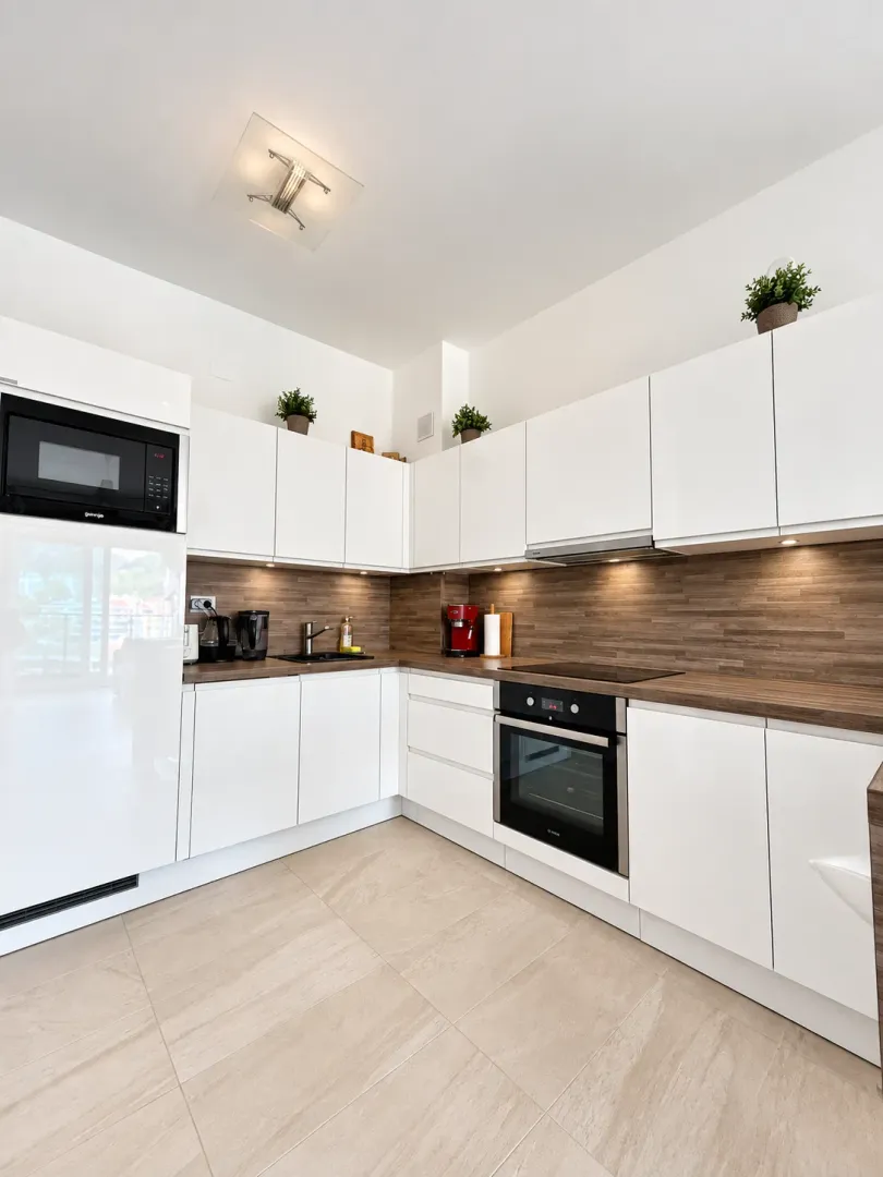 Modern white kitchen with wooden countertops.