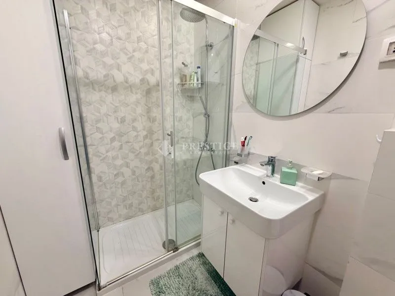 Modern bathroom with a shower cabin, washbasin, and mirror.