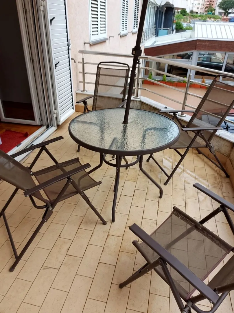 Namtještena terasa sa stolom, stolicama i suncobranom.