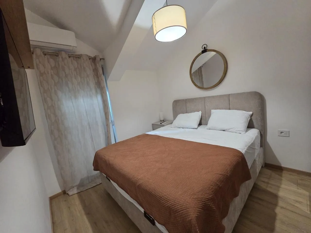 Bedroom with a double bed, wall mirror, and sloping ceiling.