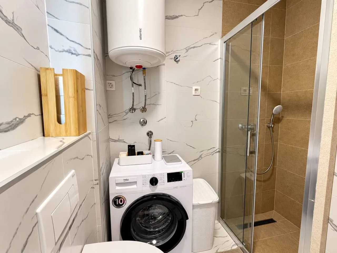 Modern bathroom with a shower cabin, washing machine, and water heater.