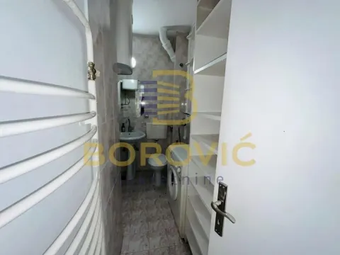 Manje kupatilo sa sanitarijama, tušem i ugrađenim policama pored vrata. - image 2