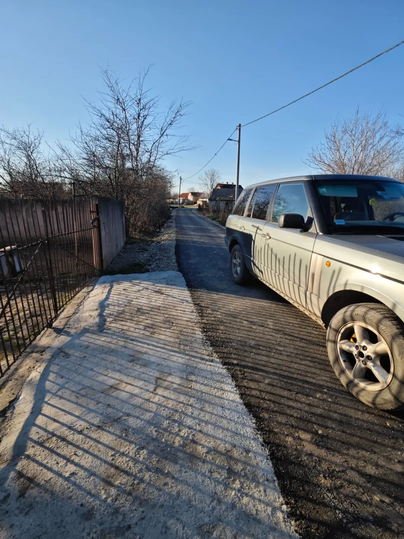 Pogled na ulicu ispred kuće sa parkiranim automobilom.