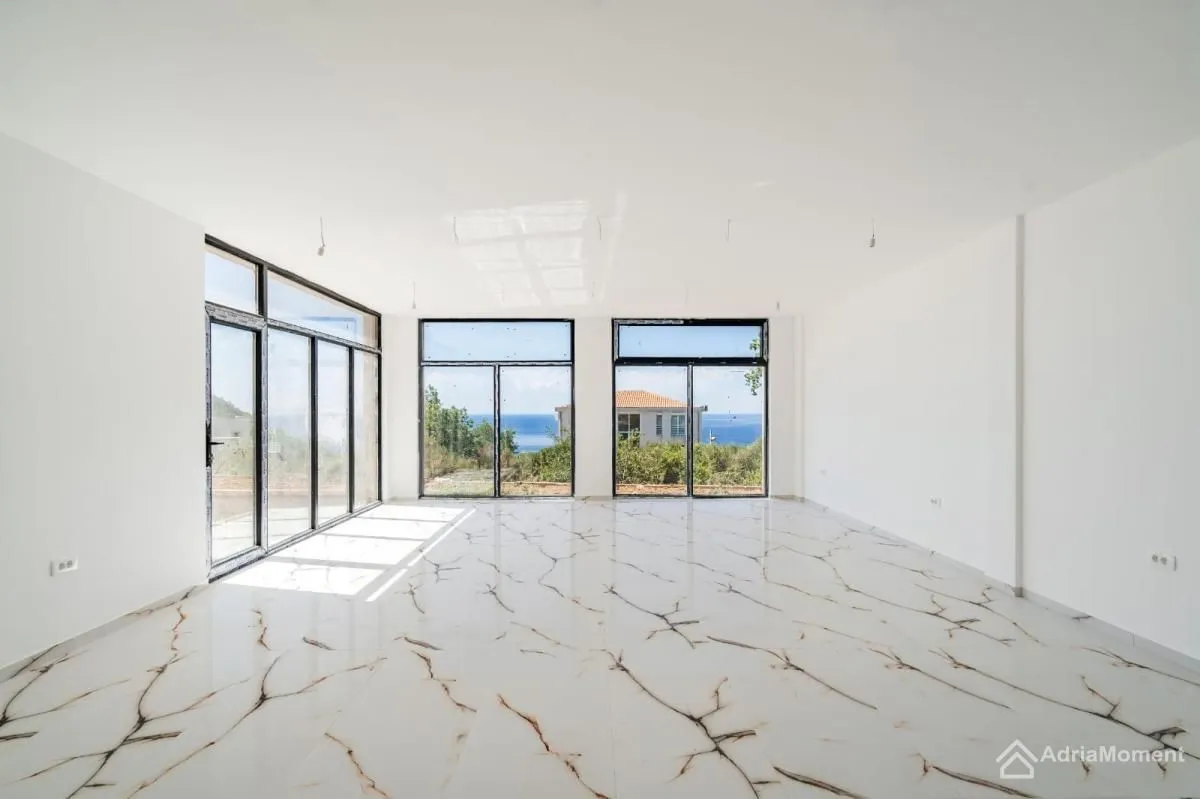 Empty living room with large glass surfaces and a sea view.