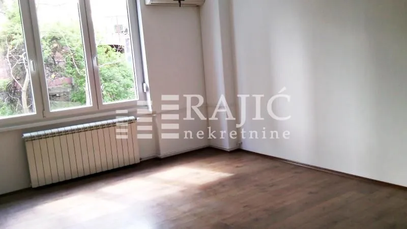 Empty room with wooden flooring and a window.