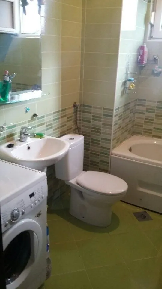A simple bathroom with a bathtub, sink, and washing machine.