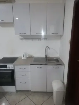 A small kitchen with white cabinets, a sink, and a stove. - image 3