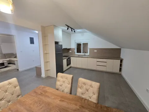 Kuhinja sa elementima u bež tonovima i trpezarijskim stolom u prvom planu. - image 7