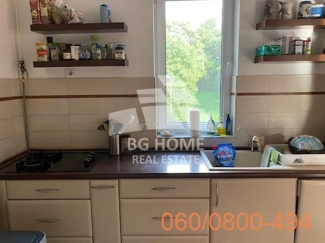 Manja kuhinja sa sudoperom, šporetom i zidnim policama.